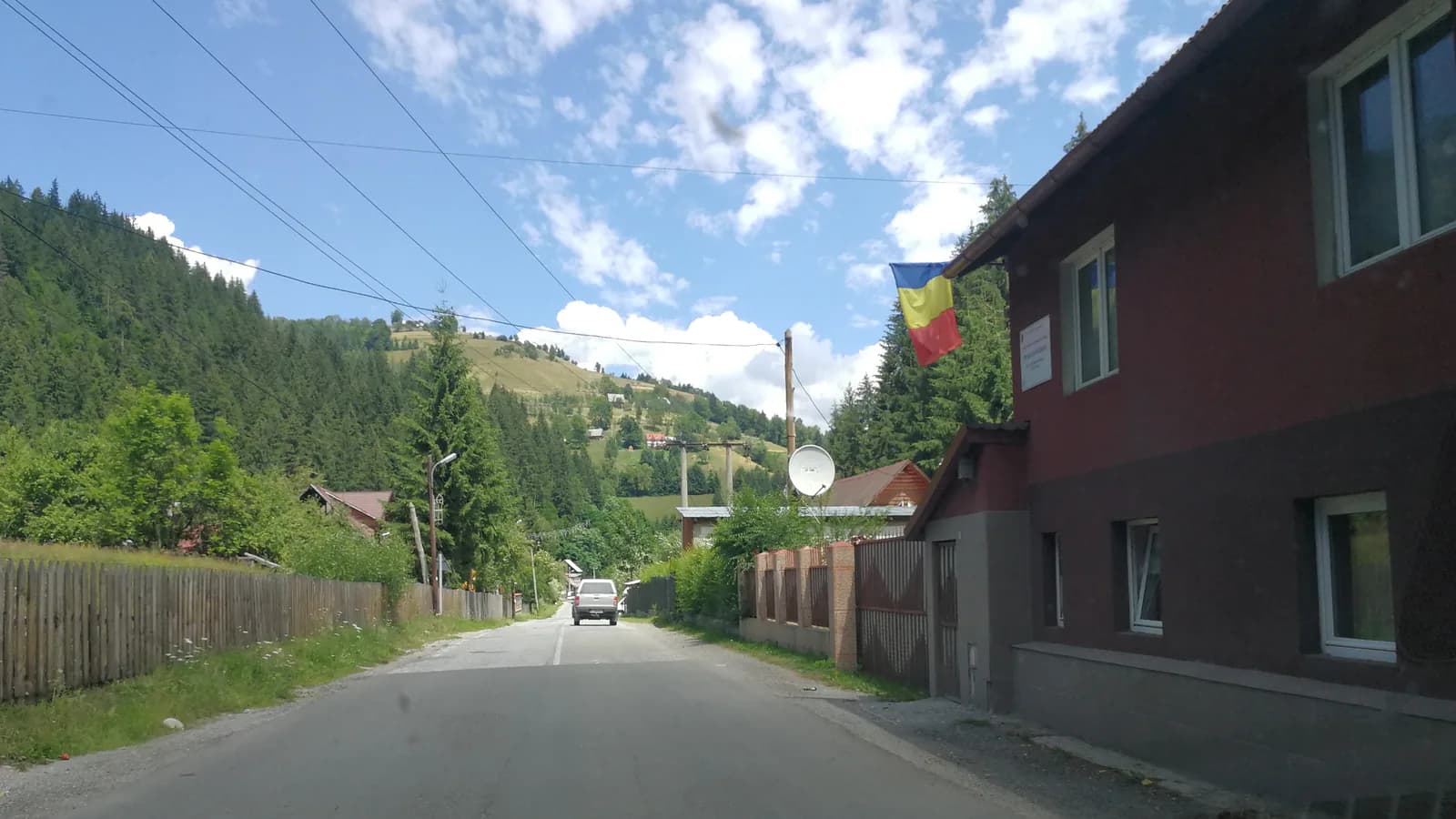 Drum prin Scărișoara, între case și versanții împăduriți ai Apusenilor