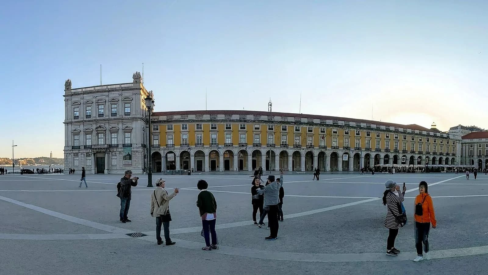Panoramă a Praça do Comércio și a frontului de clădiri galbene spre Tejo