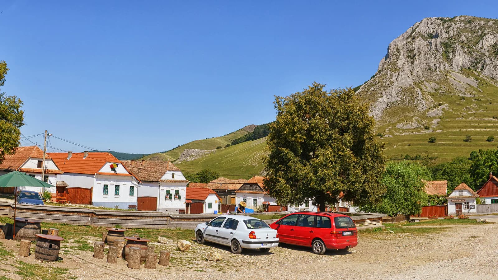 Piața din Rimetea, cu case albe și Piatra Secuiului ridicându-se în fundal