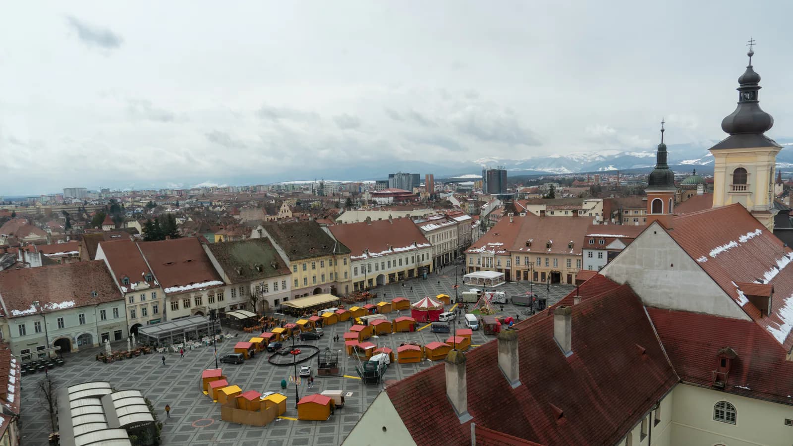 Piața Mare din Sibiu văzută de sus, cu acoperișurile orașului și Carpații în depărtare