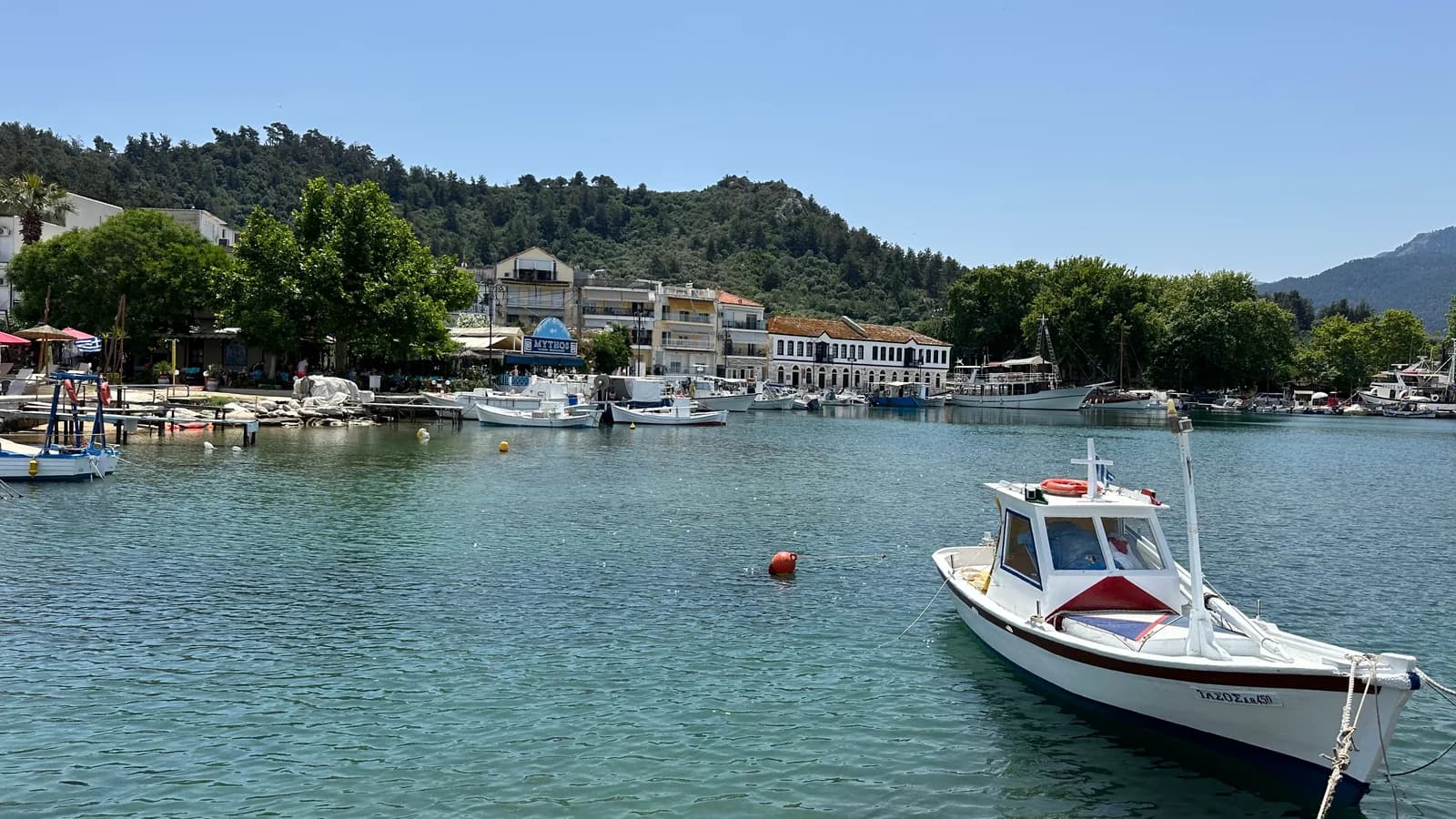 Port mic cu bărci și deal împădurit în Thassos